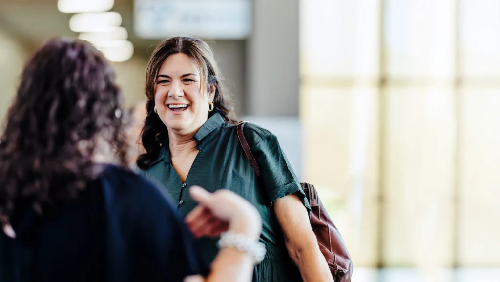 Women sharing a joyful conversation in the Trinity Baptist Church lobby — connection through adult ministry in Lake Charles