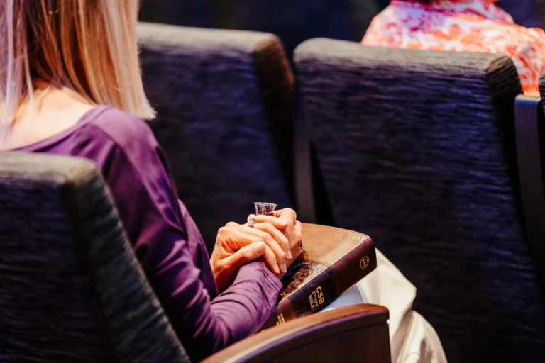 Woman holding communion cup and Bible during Lord’s Supper service.