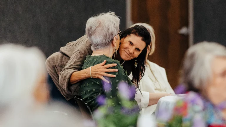 Woman warmly hugging a widow during a WINGS ministry gathering at Trinity Baptist Church.