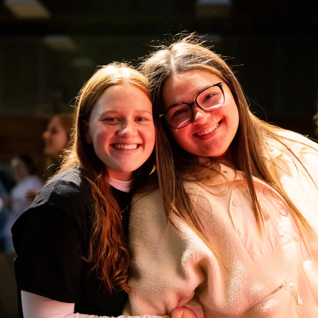 Friends smiling at a youth student homegroup gathering indoors.
