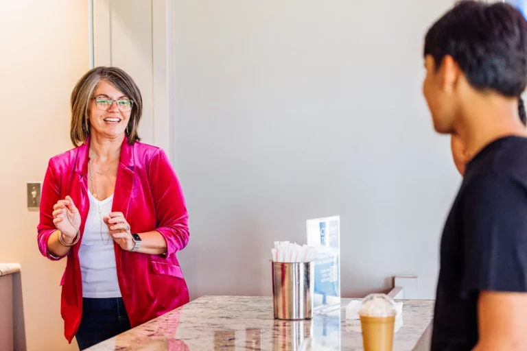Smiling café volunteer greeting a guest at Trinity Baptist Church coffee station.