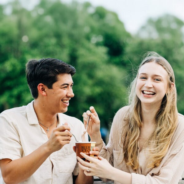 Happy couple laughing and enjoying ice cream together on a park bench