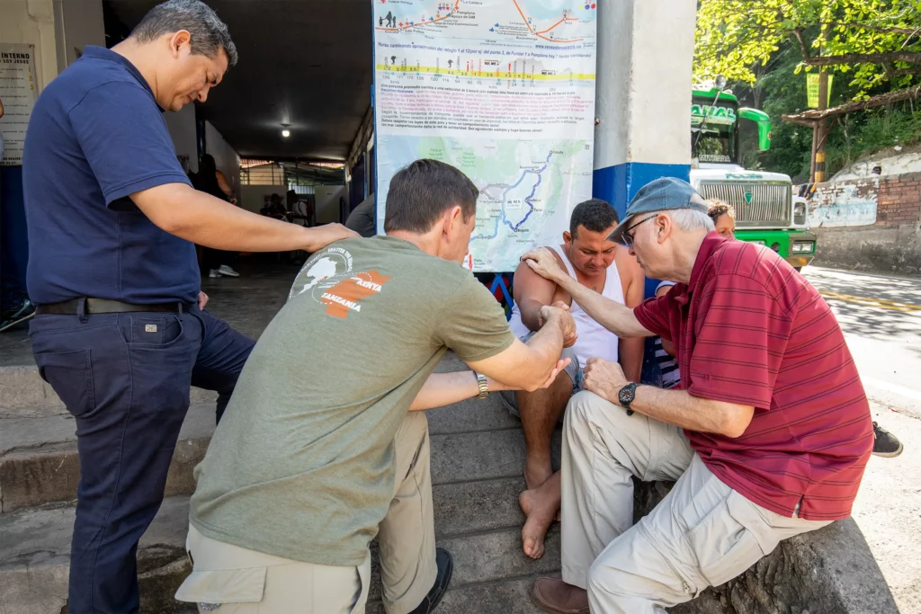 A mission team praying with a man on a street in Colombia