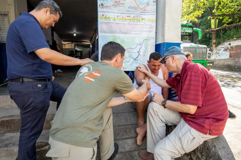 A mission team praying with a man on a street in Colombia