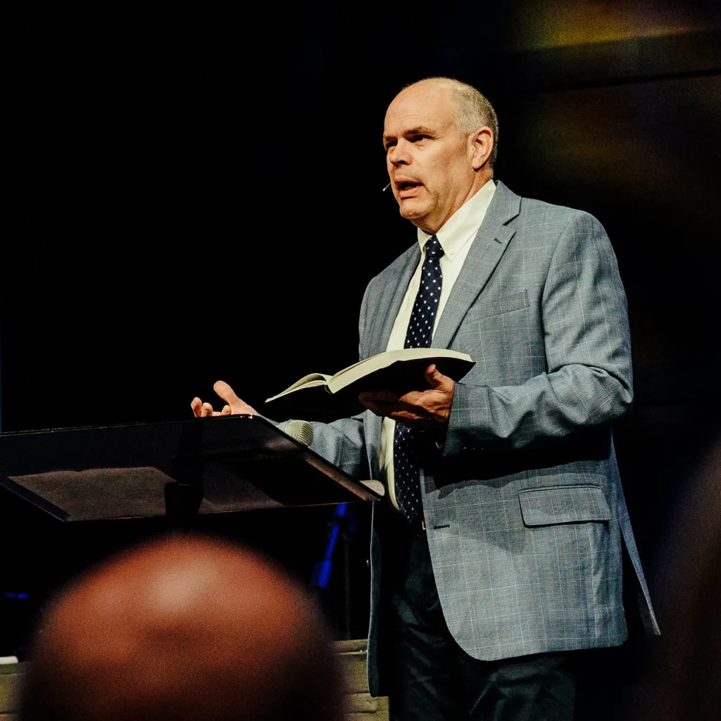 Dr. David Rose preaching at Trinity Baptist Church with Bible in hand