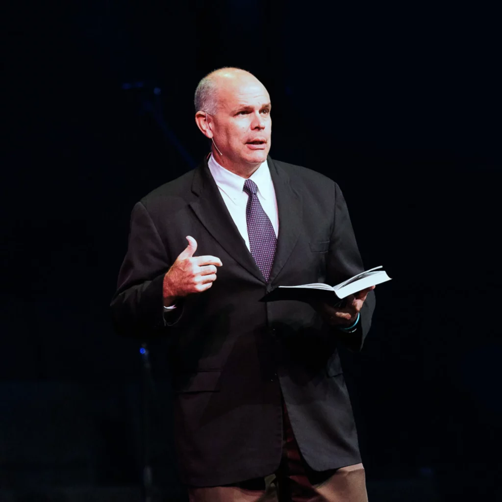 Pastor David Rose teaching from Scripture on stage in a sermon.