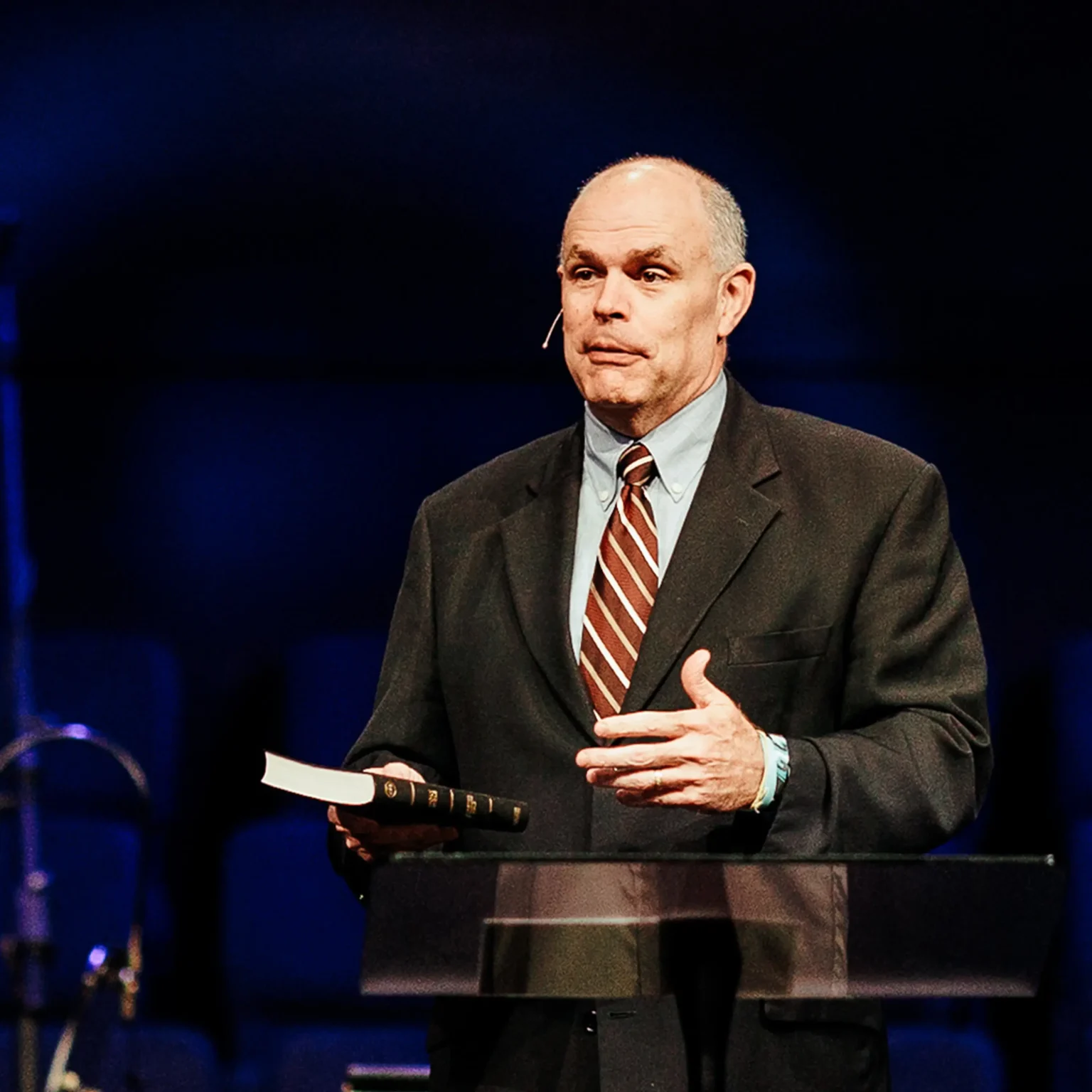 Dr. David Rose holding a Bible while preaching about purpose in Christ.