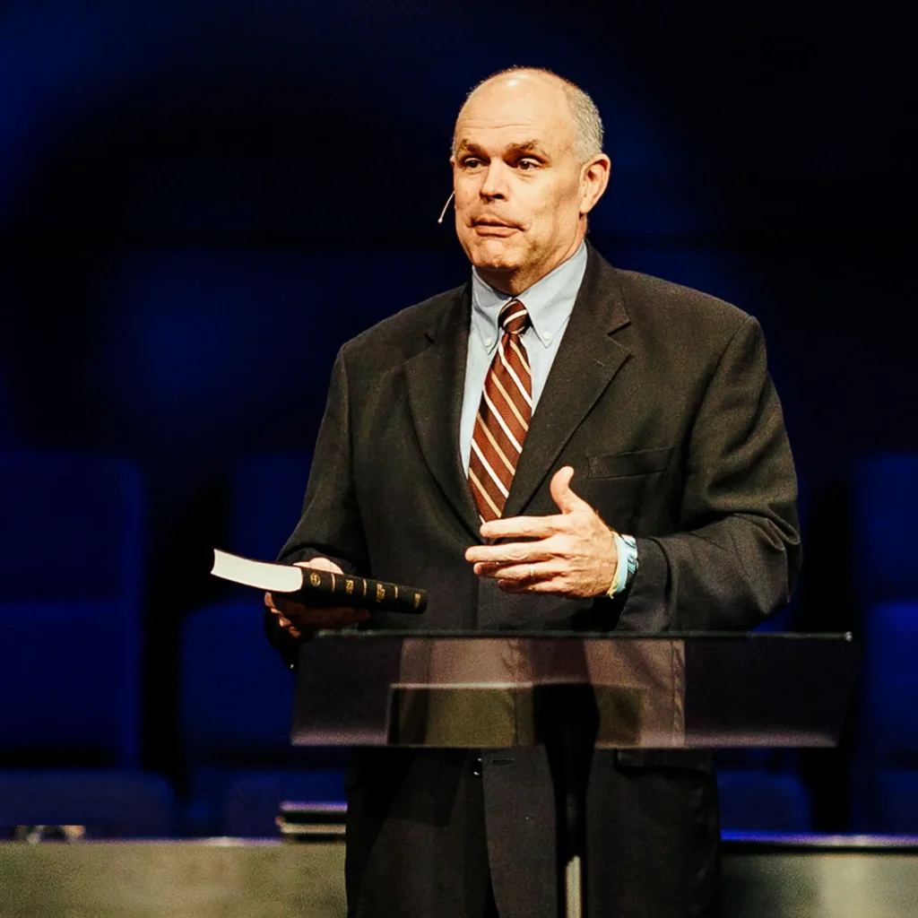 Pastor David Rose preaching at Trinity Baptist Church holding a Bible.