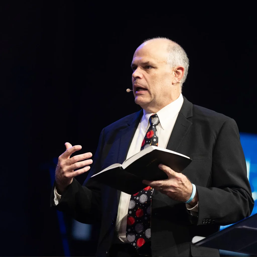 Pastor David Rose preaching at Trinity Baptist Church with an open Bible.