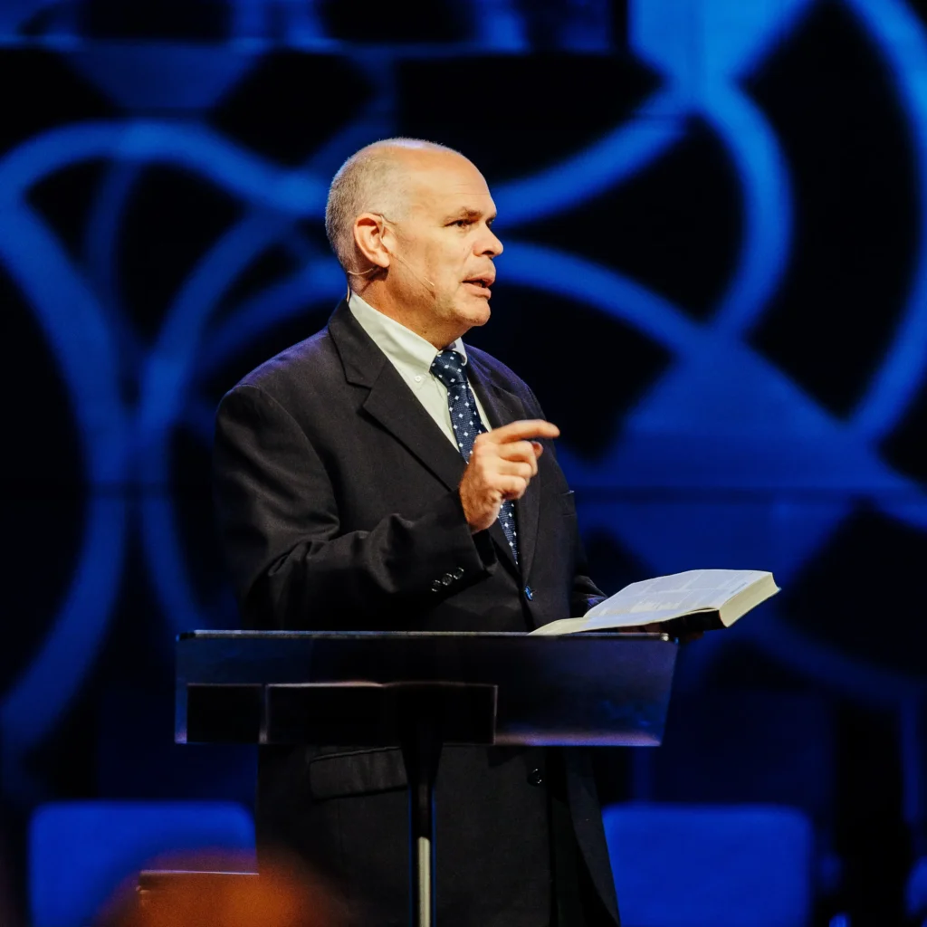 Pastor David Rose speaking with open Bible at Trinity Baptist Church.