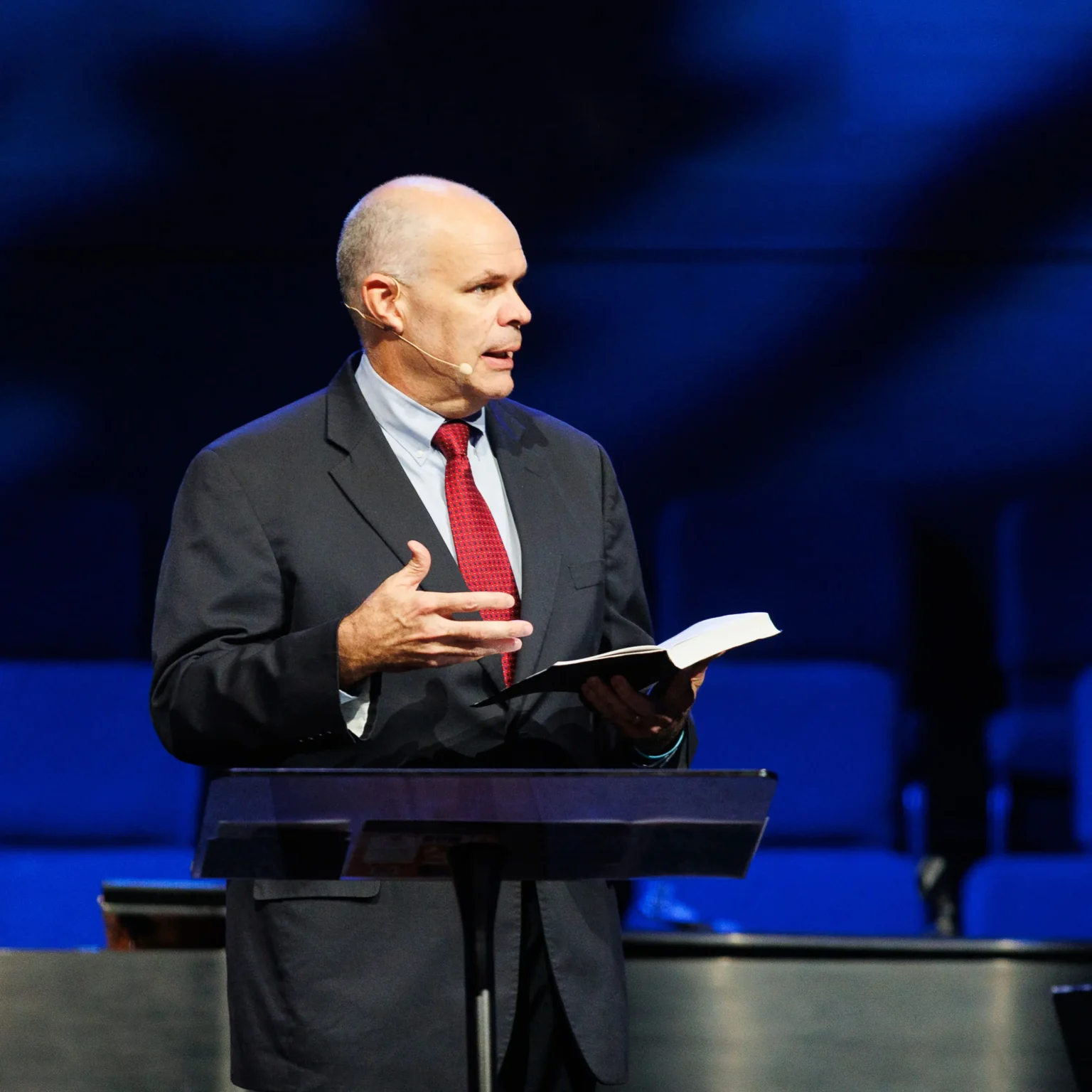 Pastor David Rose preaching at Trinity Baptist Church holding an open Bible.