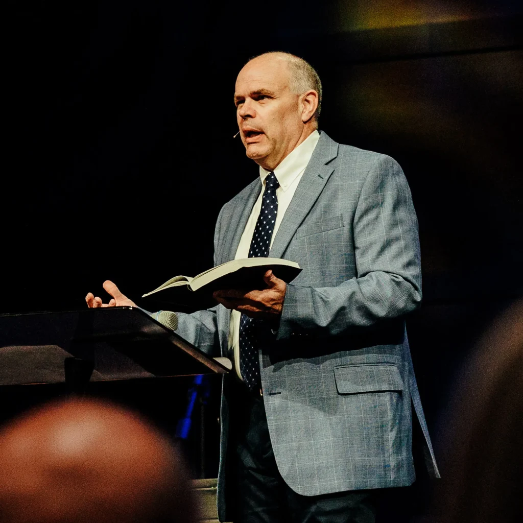 Pastor David Rose holding an open Bible at the pulpit during a Sunday sermon at Trinity Baptist Church in Lake Charles