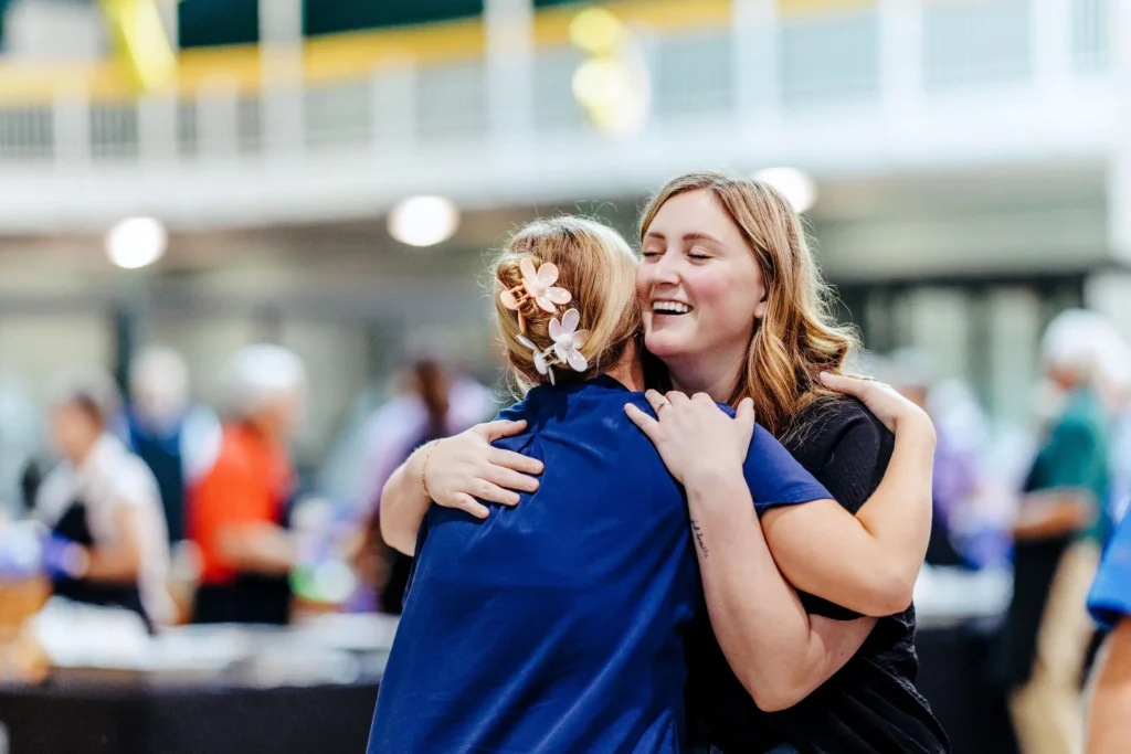 Two young women share a joyful hug at Trinity Baptist Church's Young Adult Vision Night.
